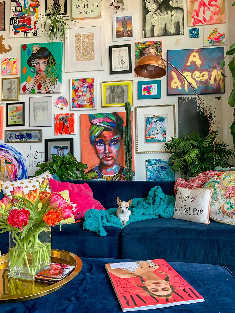 Rob's colorful apartment living room with a navy velvet sofa, gallery art wall, flowers, and a small dog